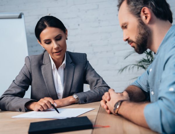 selective focus of brunette lawyer holding pen near insurance documents and bearded client